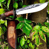 Decorative knife with wooden sheath on a tree trunk surrounded by green leaves